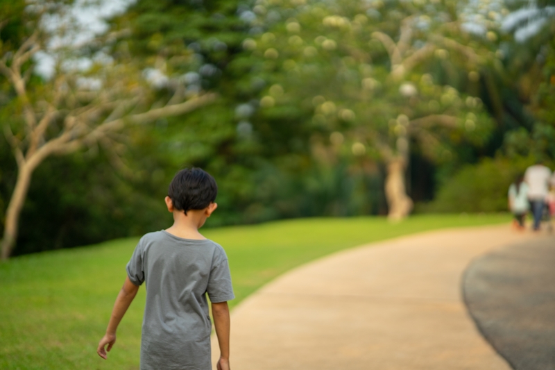 Asian young boy walking alone in the park.
